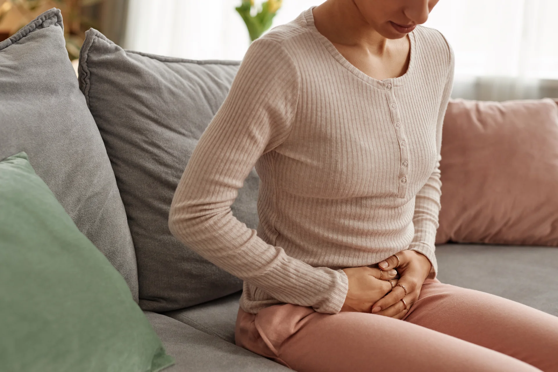 woman on couch with abdominal discomfort 2026 03 19 09 17 29 utc